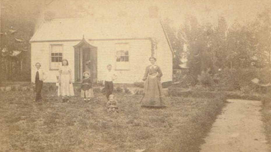 A group of people standing in front of a house
Description automatically generated